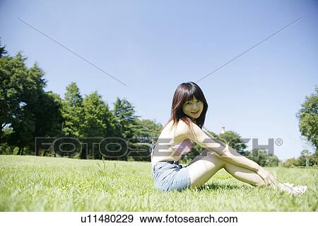 Stock Photo - A young woman sitting in park. Fotosearch