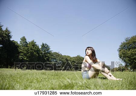 Stock Photography - A young woman sitting in park. Fotosearch
