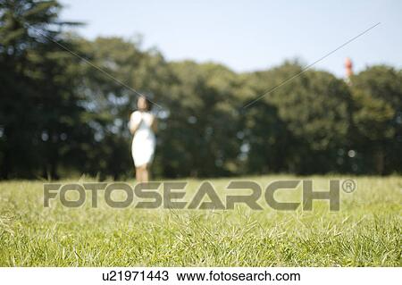 A young woman standing in park View Large Photo Image Stock Image - A young woman standing in park. Fotosearch