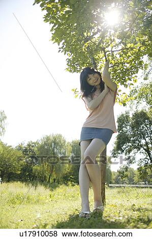 Stock Photo - A young woman standing under a tree. Fotosearch