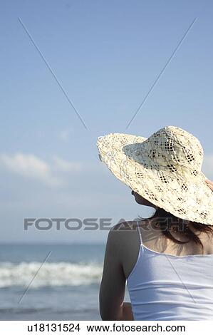 A young woman wearing a hat in beach, rear view View Large Photo Image Picture - A young woman wearing a hat in beach, rear view. Fotosearch