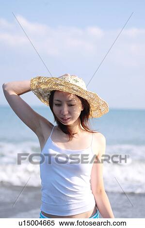 Stock Photography - A young woman wearing a hat in beach. Fotosearch