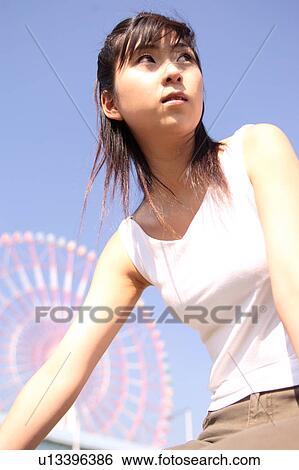 Stock Photograph - A woman in front of Ferris Wheel. Fotosearch