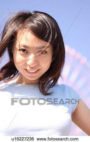 Stock Photograph - A woman standing in front of Ferris Wheel. Fotosearch