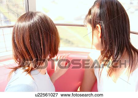 Stock Photo - Two women in Ferris Wheel, Rear View. Fotosearch