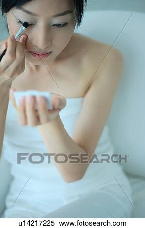 Stock Photography - A young woman applying eye makeup, close-up. Fotosearch