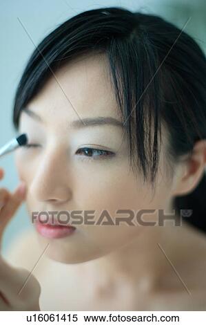 A young woman applying eye makeup, close-up View Large Photo Image Stock Photography - A young woman applying eye makeup, close-up. Fotosearch