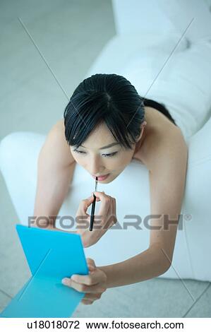 Stock Image - A young woman applying lipstick. Fotosearch