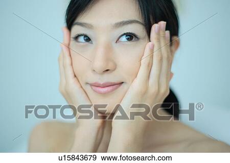 A young woman applying lotion to her face View Large Photo Image Stock Photo - A young woman applying lotion to her face. Fotosearch