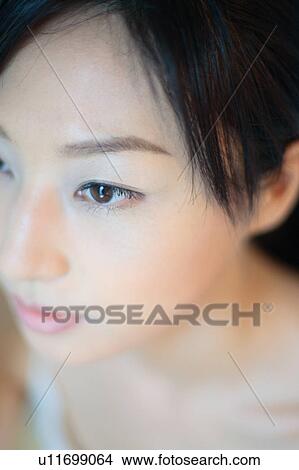 Picture - A young woman applying makeup, close-up. Fotosearch