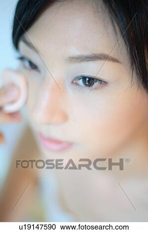 A young woman applying makeup, close-up View Large Photo Image Stock Image - A young woman applying makeup, close-up. Fotosearch