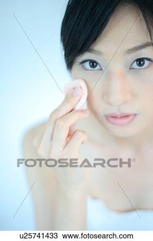 Stock Image - A young woman applying makeup, close-up. Fotosearch