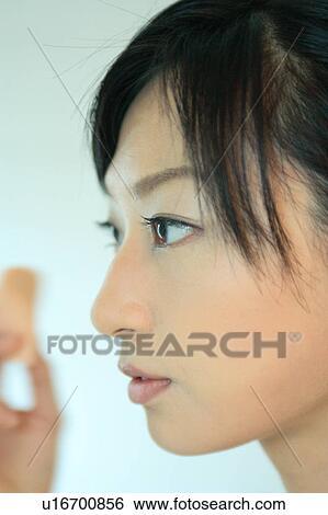 Stock Photograph - A young woman applying makeup, close-up. Fotosearch