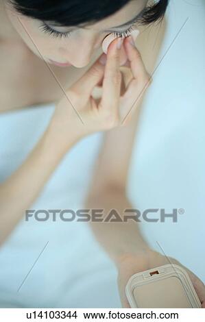 Picture - A young woman applying makeup. Fotosearch