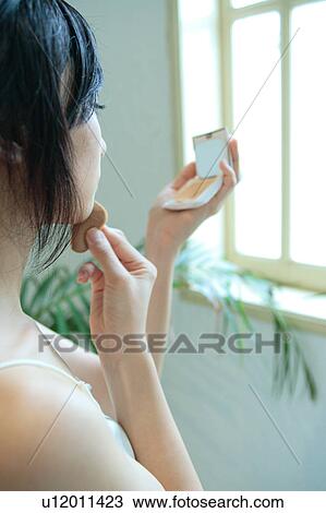 A young woman applying makeup, rear view View Large Photo Image Stock Image - A young woman applying makeup, rear view. Fotosearch