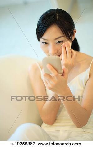 Stock Image - A young woman applying makeup. Fotosearch