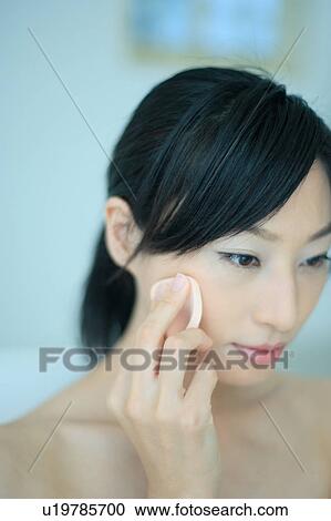 Stock Image - A young woman applying makeup. Fotosearch