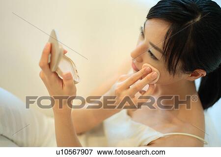 Stock Photo - A young woman applying makeup. Fotosearch