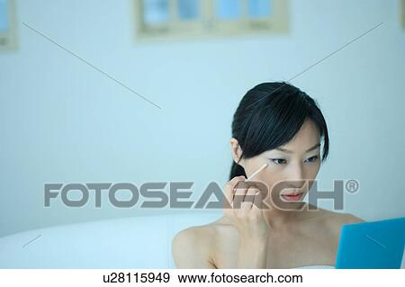 A young woman applying makeup View Large Photo Image Stock Photo - A young woman applying makeup. Fotosearch