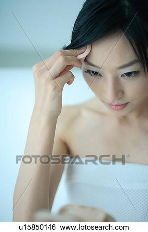 A young woman applying makeup View Large Photo Image Stock Photograph - A young woman applying makeup. Fotosearch