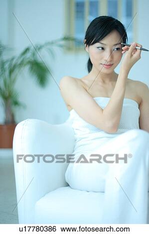 Stock Photograph - A young woman applying makeup. Fotosearch