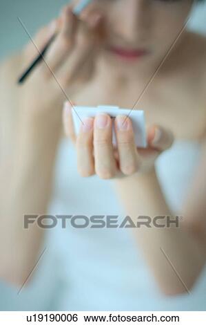 Stock Photograph - A young woman applying makeup. Fotosearch