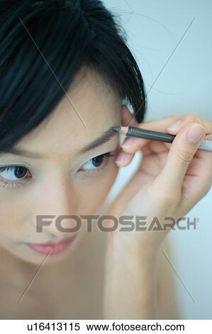 Stock Photography - A young woman applying makeup. Fotosearch