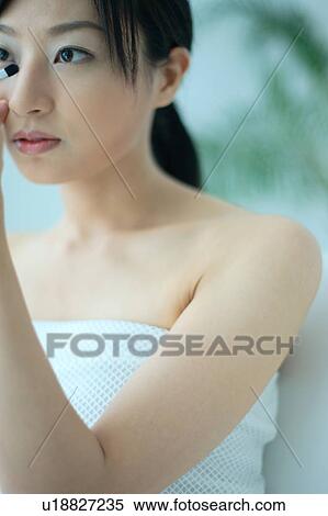 Stock Photography - A young woman applying makeup. Fotosearch