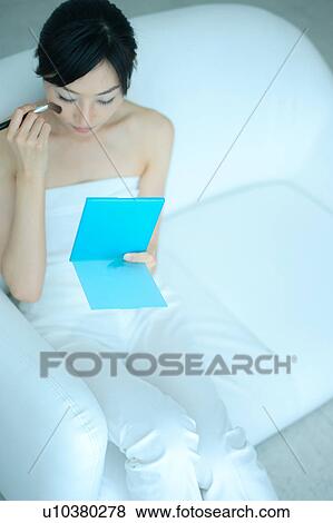 A young woman applying makeup with brush View Large Photo Image Stock Photo - A young woman applying makeup with brush. Fotosearch