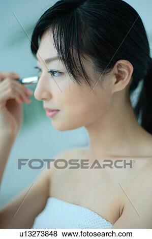 A young woman applying makeup with brush View Large Photo Image Stock Photo - A young woman applying makeup with brush. Fotosearch