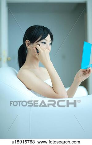 Stock Photo - A young woman applying makeup with brush. Fotosearch