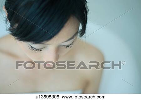 Stock Photography - A young woman looking down, close-up. Fotosearch