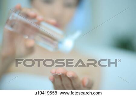 A young woman pouring lotion into hand View Large Photo Image Stock Photo - A young woman pouring lotion into hand. Fotosearch