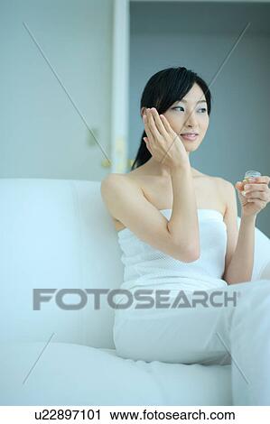 Stock Image - A young woman putting moisturizer to face. Fotosearch