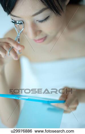 A young woman using eyelash curler View Large Photo Image Stock Photograph - A young woman using eyelash curler. Fotosearch