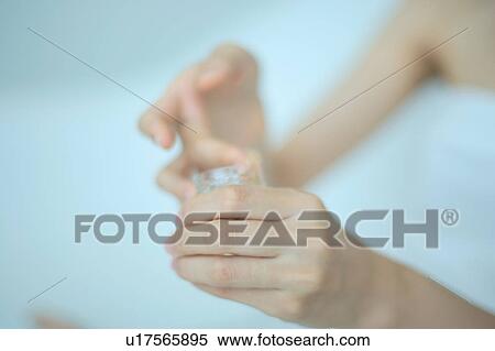 Stock Photography - Close-up of a hand holding moisturizer. Fotosearch