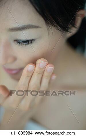 Close-up of a young woman putting moisturizer to face View Large Photo Image Picture - Close-up of a young woman putting moisturizer to face. Fotosearch
