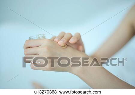Close-up of a young woman putting moisturizer to hand View Large Photo Image Stock Photo - Close-up of a young woman putting moisturizer to hand. Fotosearch