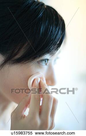 Stock Photography - Profile of a young woman applying makeup, close-up. Fotosearch