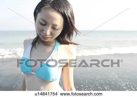A young woman in bikini standing at beach View Large Photo Image Picture - A young woman in bikini standing at beach. Fotosearch