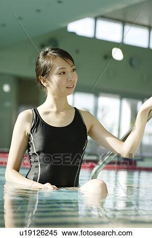 Stock Photography - A young woman in swim wear standing in pool. Fotosearch