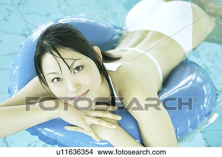 Picture - A young woman playing with inner tube in pool. Fotosearch