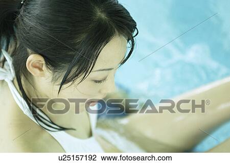 Stock Image - A young woman playing with inner tube in pool. Fotosearch