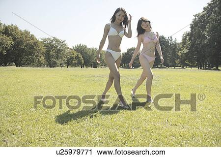 Tow young women in bikini walking in park View Large Photo Image Stock Image - Tow young women in bikini walking in park. Fotosearch