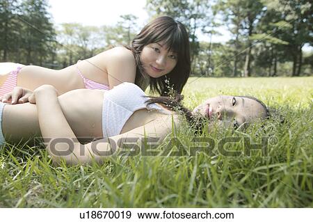 Stock Photo - Two young women in bikini lying down on lawn. Fotosearch