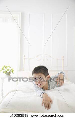 Stock Photo - A boy lying on bed. Fotosearch