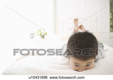 A boy lying on bed View Large Photo Image Stock Photograph - A boy lying on bed. Fotosearch