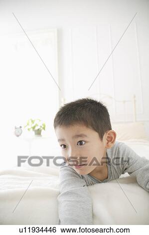 Stock Photograph - A boy lying on bed. Fotosearch