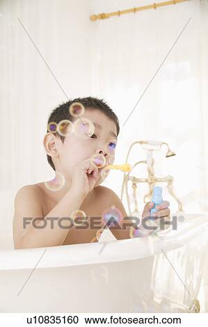Stock Image - A boy plying with bubbles in bathroom. Fotosearch