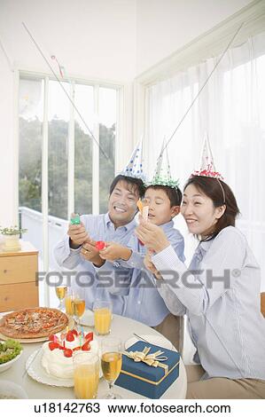 Stock Image - Family celebrating birthday at home. Fotosearch